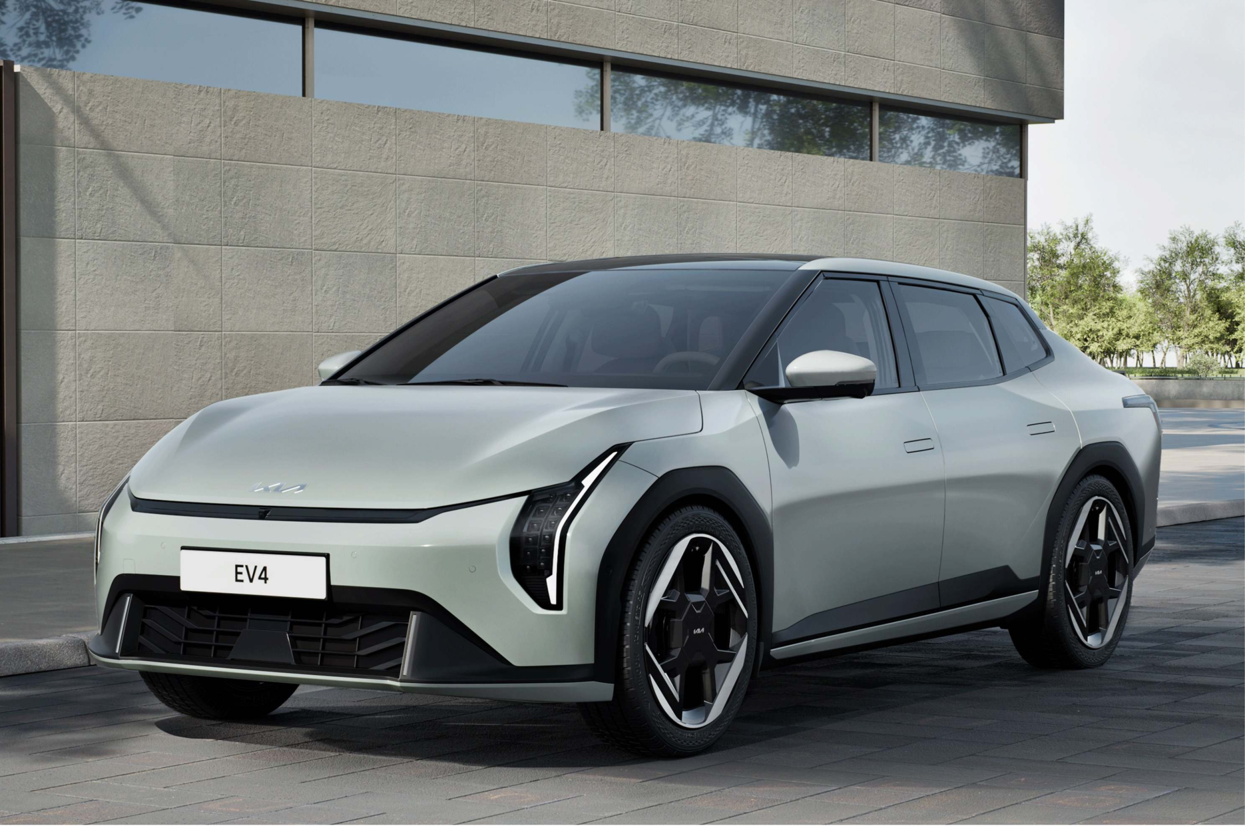 Zwei Personen stehen unter einem aufgebockten Auto in einer Werkstatt. Eine Person hält eine Lampe und zeigt auf einen Bereich unter dem Fahrzeug, während die andere aufmerksam zuhört.