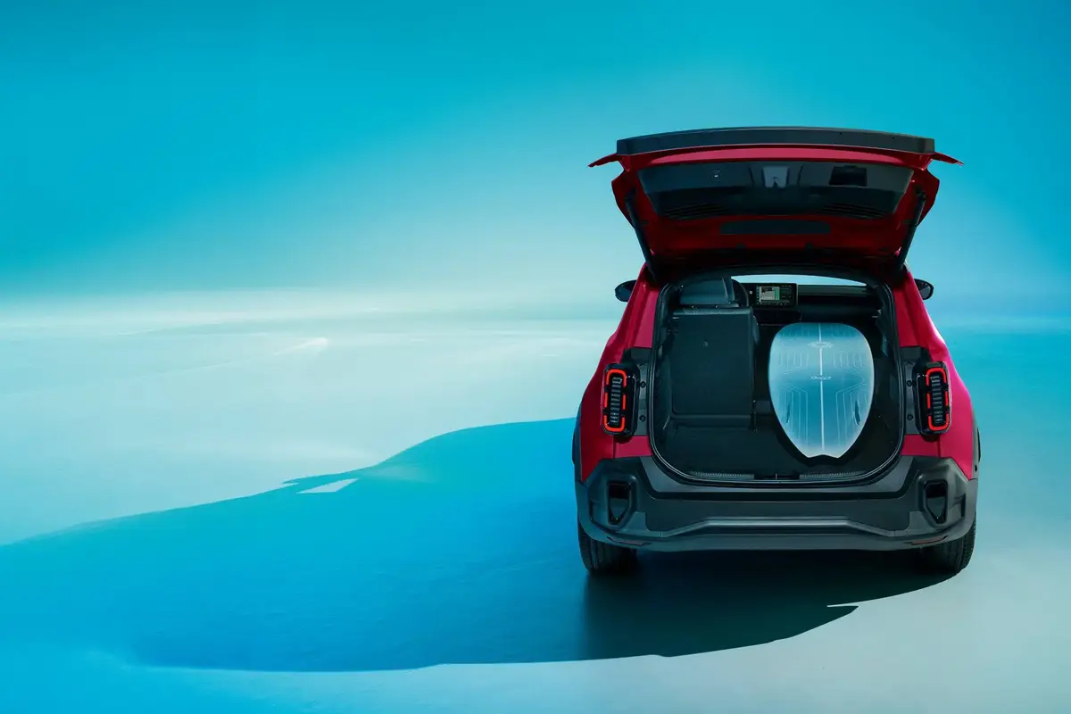 Roter R4 mit geöffneten Kofferraum, es liegt ein Surfboard drinnen
