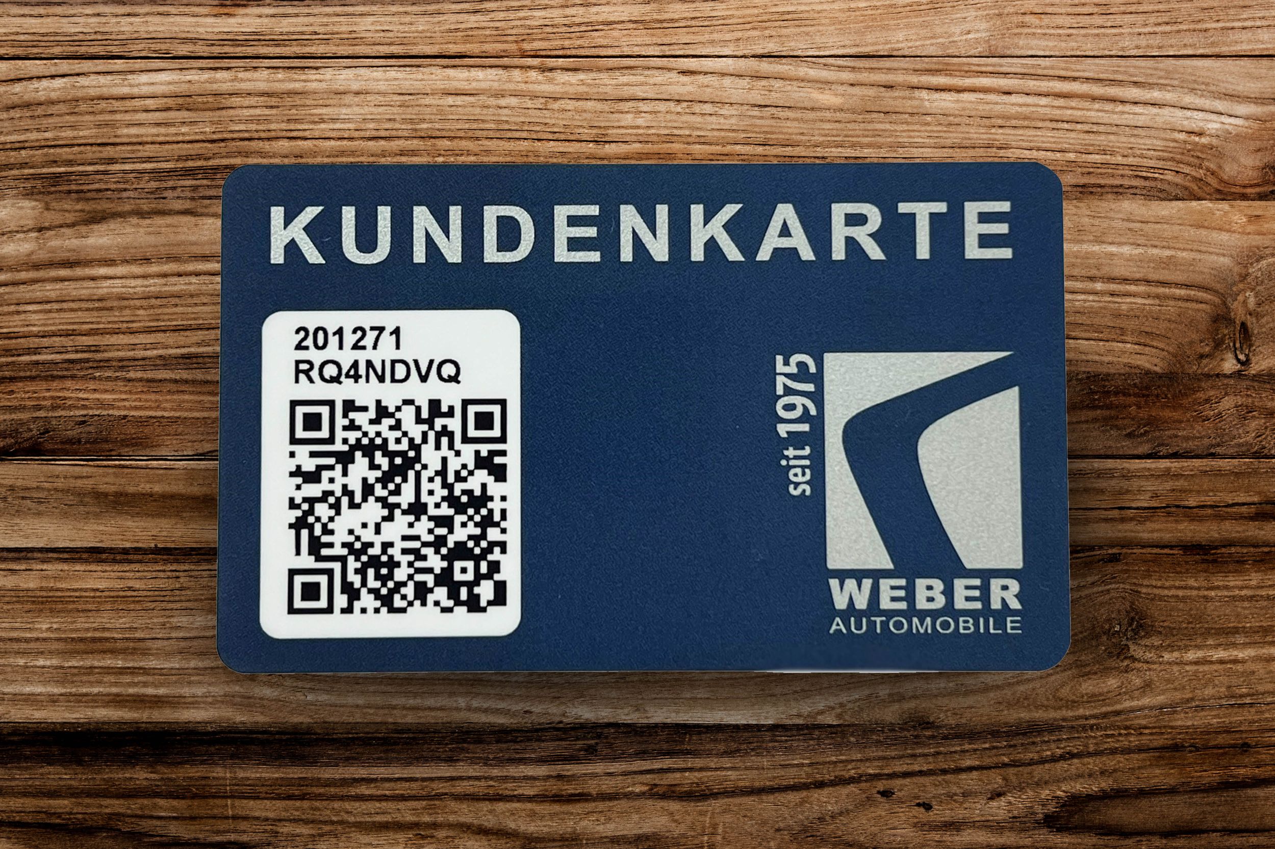 Kundenkarte von WEBER AUTOMOBILE, die auf einem Holztisch liegt.