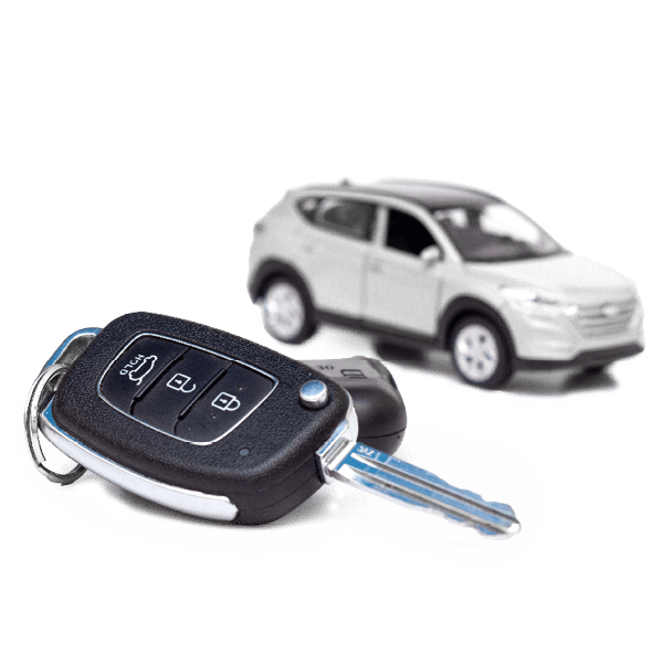 Autoschlüssel mit Fernbedienung im Vordergrund und ein silbernes Modellauto im Hintergrund.